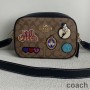 Torba fotograficzna Coach Jamie z płótna Signature Canvas z naszywkami Disneya w kolorze khaki